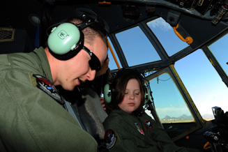 An image of a Davis-Monthan AFB pilot helping a disabled child be involved in the "Pilot for a Day" program.
